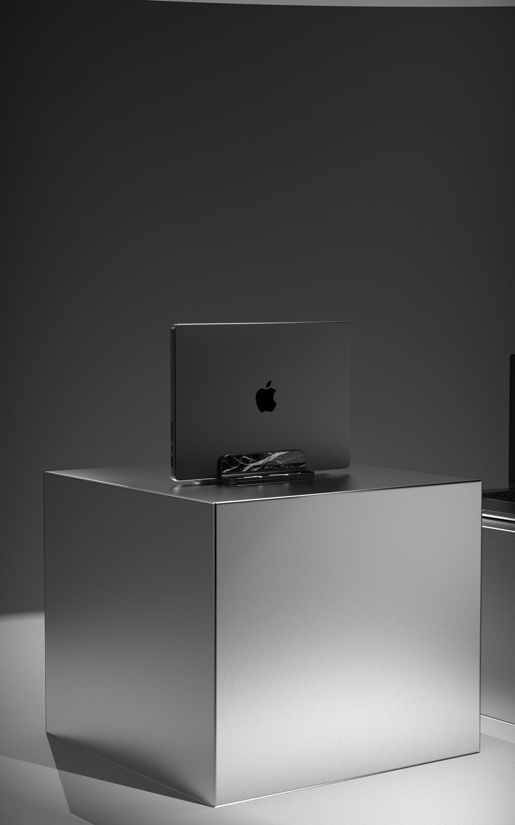 Marble Fusion Stand en mármol Nero Marquina para MacBook e iPad, con un MacBook sobre fondo oscuro