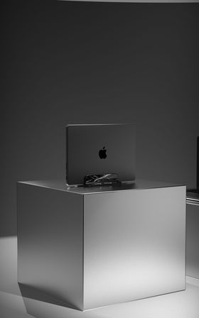 Marble Fusion Stand en mármol Nero Marquina para MacBook e iPad, con un MacBook sobre fondo oscuro
