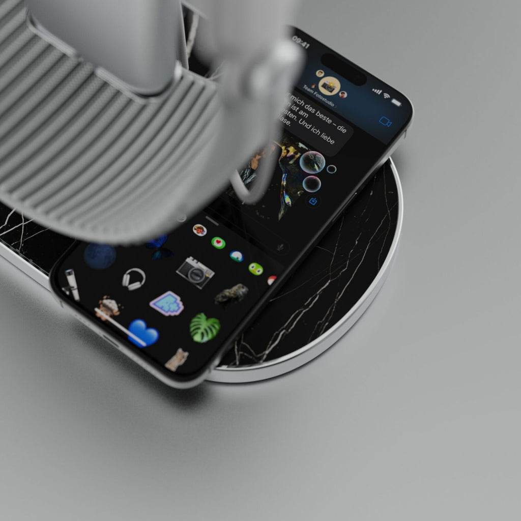 Soporte para Apple Vision Pro con base de mármol Nero Marquina, con un Apple Vision Pro y un iPhone en la zona de carga