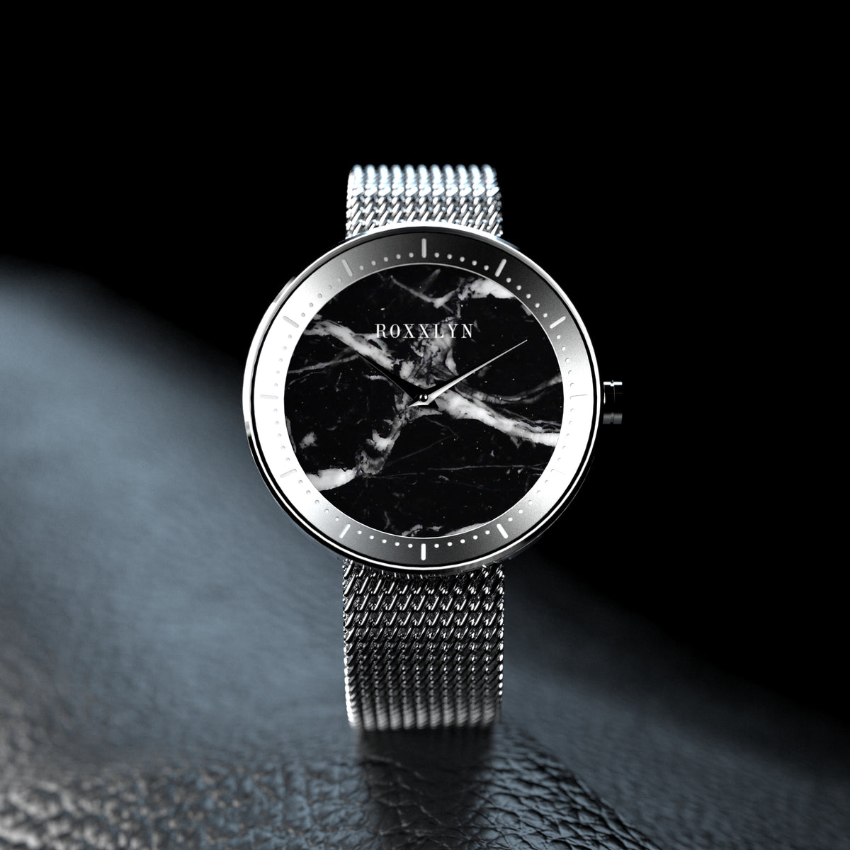 ROXXLYN Marble Watch mit Nero Marquina Zifferblatt und silbernem Milanaise-Armband, auf dunkler Fläche im Streiflicht