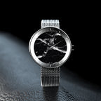 ROXXLYN Marble Watch mit Nero Marquina Zifferblatt und silbernem Milanaise-Armband, auf dunkler Fläche im Streiflicht